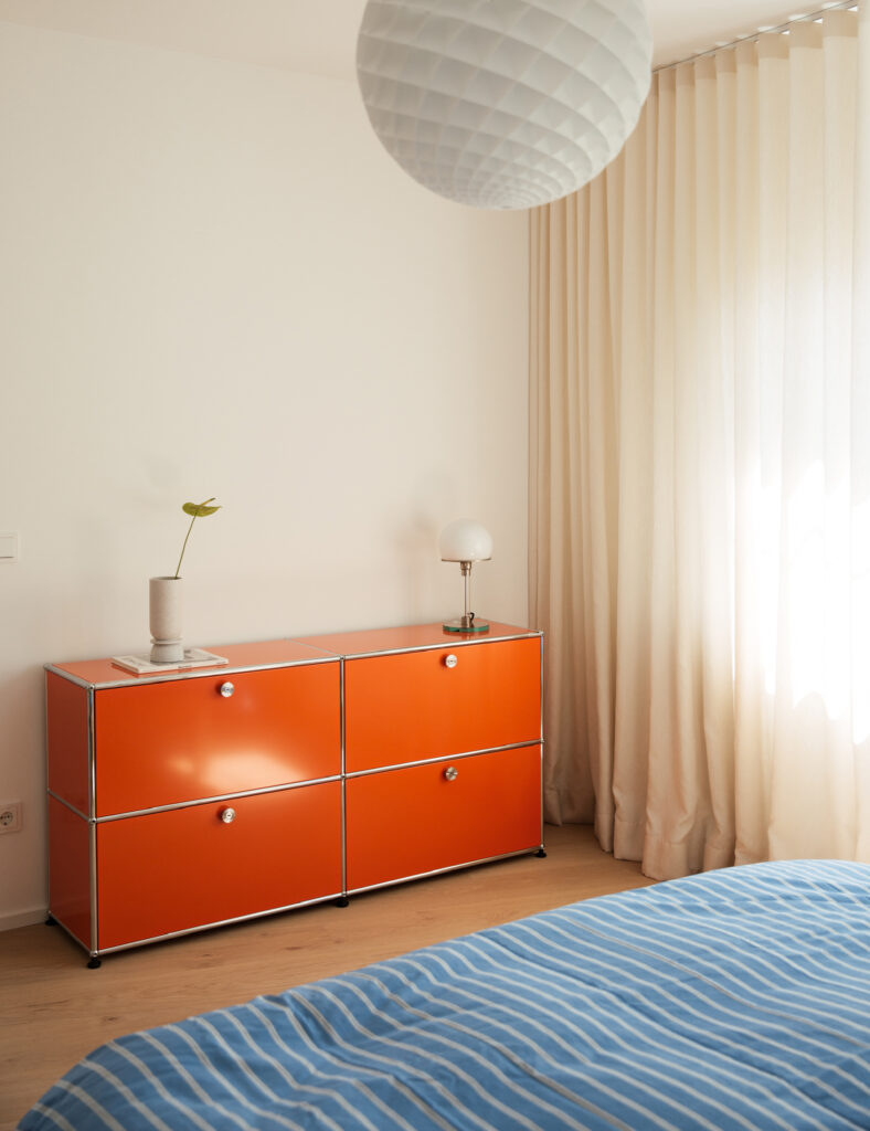 Gemütliches Bett mit gestreiftem Überwurf in einem modernen Mietstudio.