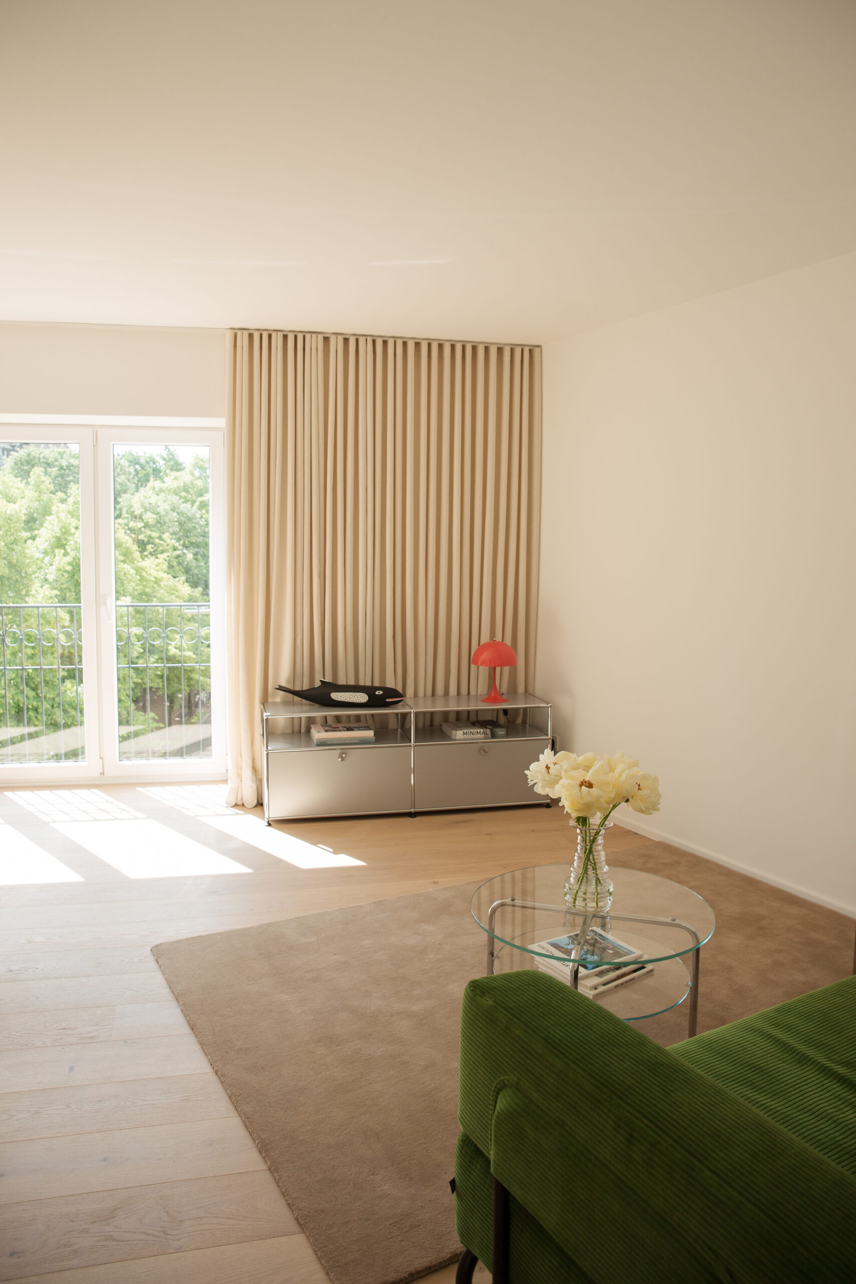 Wohnzimmer mit Couch, Couchtisch und Glasstür zur Natur in einem Mietstudio.