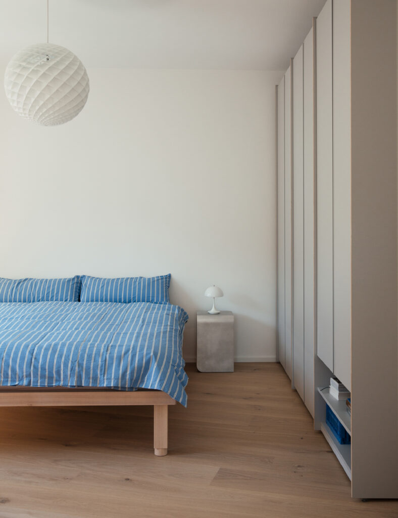 Schlafzimmer mit einem Bett und einer Kommode in einem Mietstudio, gemütlich und einladend eingerichtet.