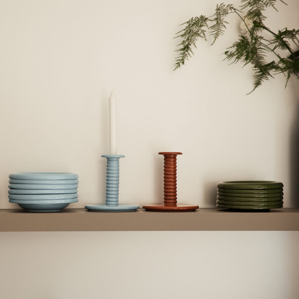 Ein Regal mit verschiedenen Geschirrstücken und Vasen in einem Mietstudio, das eine stilvolle Atmosphäre schafft.