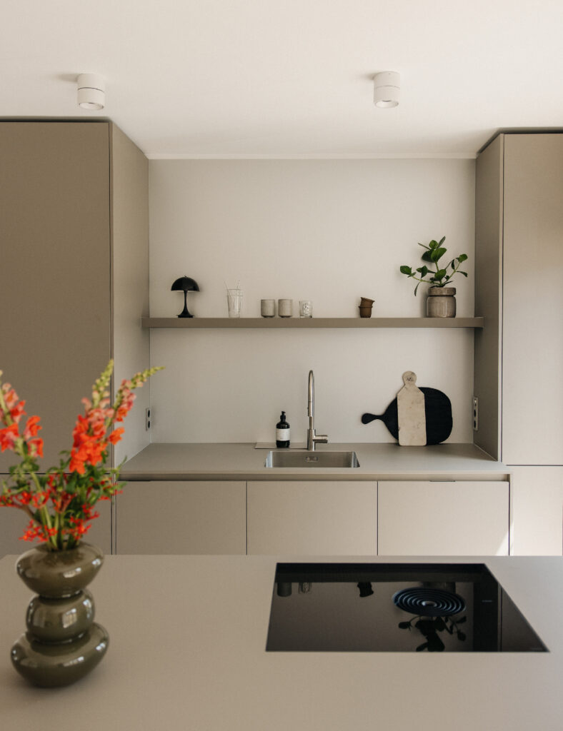 Blick auf eine stilvolle Küche mit einem Waschbecken und einer blühenden Vase in einem Mietstudio.