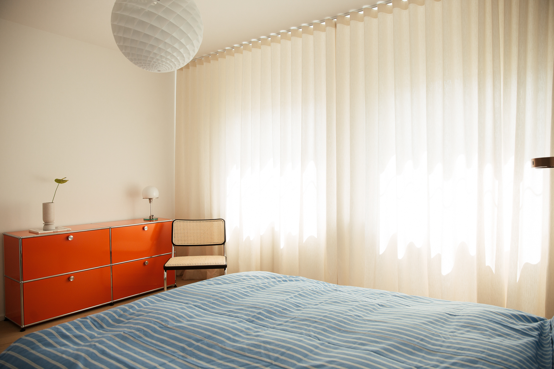 Schlafzimmer mit einem Bett, einem Stuhl und einer Lampe in einem modernen Mietstudio.